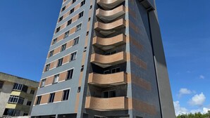 Un edificio de varios pisos con un diseño arquitectónico moderno, que presenta una combinación de fachadas de ladrillo y vidrio, y varios balcones.