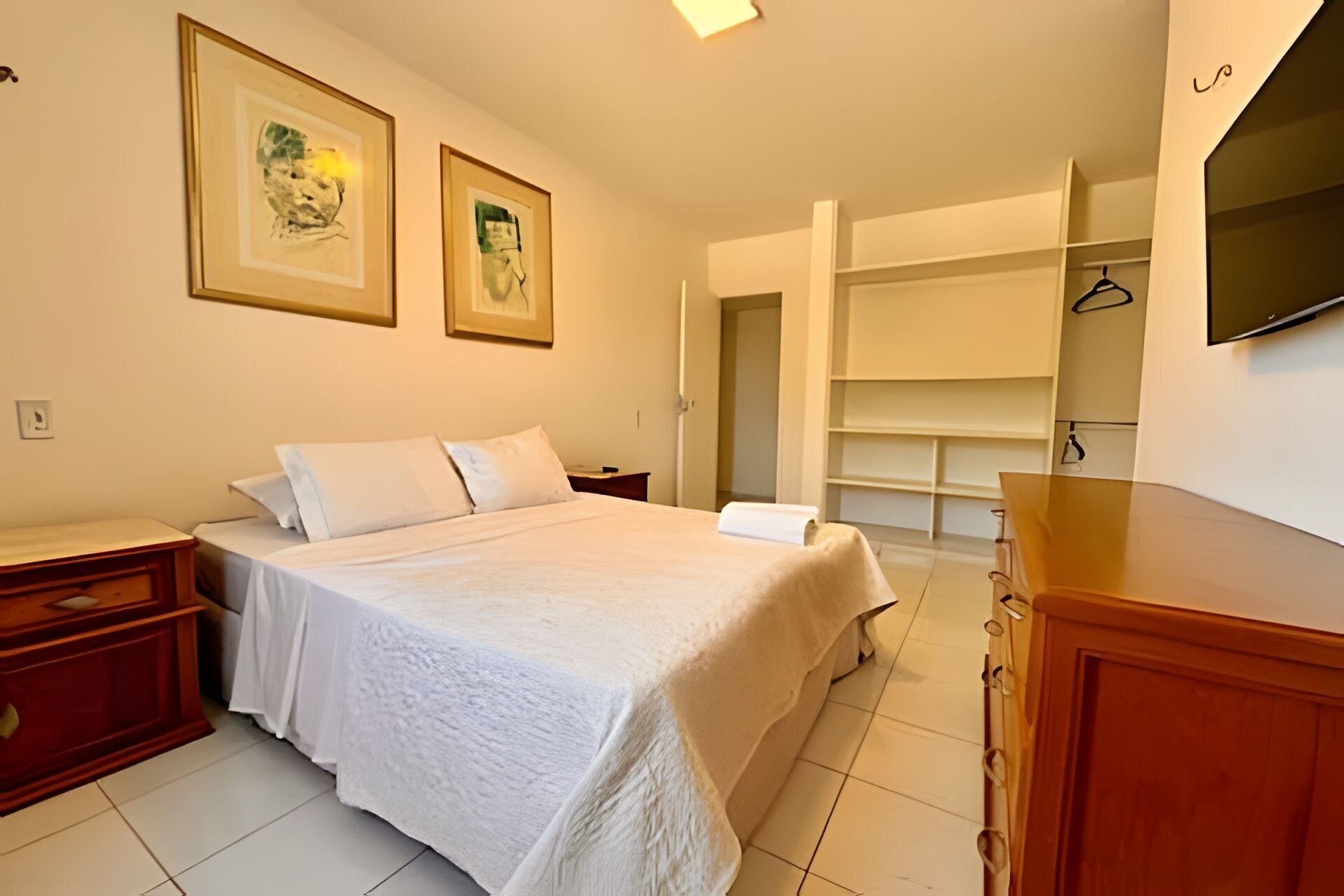 Une chambre à coucher comprenant un lit, des tables de chevet, une armoire et un téléviseur.