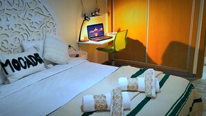 Een hotelkamer met een bed, een bureau met een laptop en decoratieve kussens.