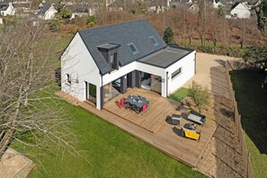 Et moderne hus med en stor terrasse, en overdækket patio og en garage.
