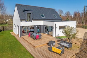 Et moderne hus med stor terrasse, spiseplads og hyggeligt opholdsområde.