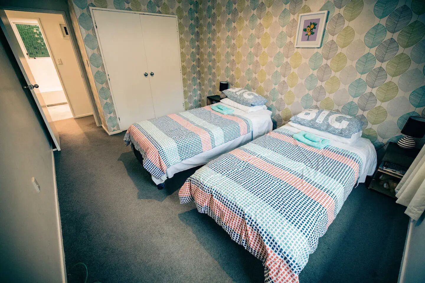 Ein Zimmer mit zwei Betten, einem Kleiderschrank und einer Wand mit Muster.