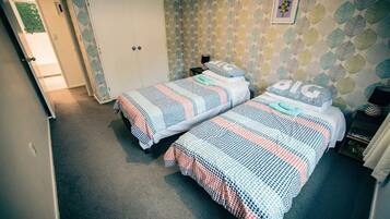 Ein Zimmer mit zwei Betten, einem Kleiderschrank und einer Wand mit Muster.