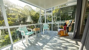 A sunlit room with large windows, a wooden rocking chair, and two white chairs with turquoise cushions. - big sale was 158 dollars now from 108 dollars (Wellington)