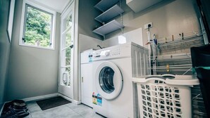 A laundry room with a front-loading washing machine, a drying rack, and a laundry basket. - big sale was 158 dollars now from 108 dollars (Wellington)