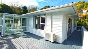 A white building with a covered deck and large windows. - big sale was 158 dollars now from 108 dollars (Wellington)