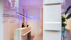 A reception desk with a neon sign, a contact phone, and a reception area with a glass wall. - Colo Colo. The Smart Hostel Valencia (Valencia)