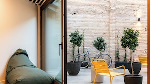 A modern outdoor seating area with a glass door, potted plants, and a bicycle. - Colo Colo. The Smart Hostel Valencia (Valencia)