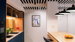 A modern kitchen with wooden cabinets, a tiled backsplash, and a dining area with a wooden table and chairs. - Colo Colo. The Smart Hostel Valencia (Valencia)