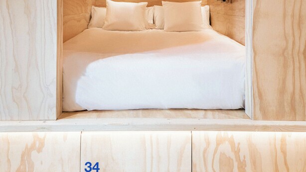 A room with a bed, a nightstand, and a mirror. The room has a wooden ceiling and walls. - Colo Colo. The Smart Hostel Valencia (Valencia)