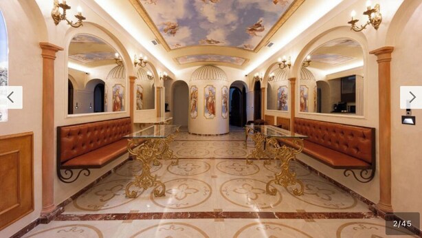 Un hall d’entrée luxueux, agrémenté de lustres somptueux, d’une table ronde centrale et de sièges confortables.