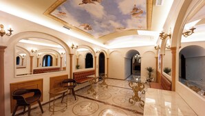 Un intérieur luxueux avec des sols en marbre, des lustres somptueux et un plafond voûté orné de fresques.