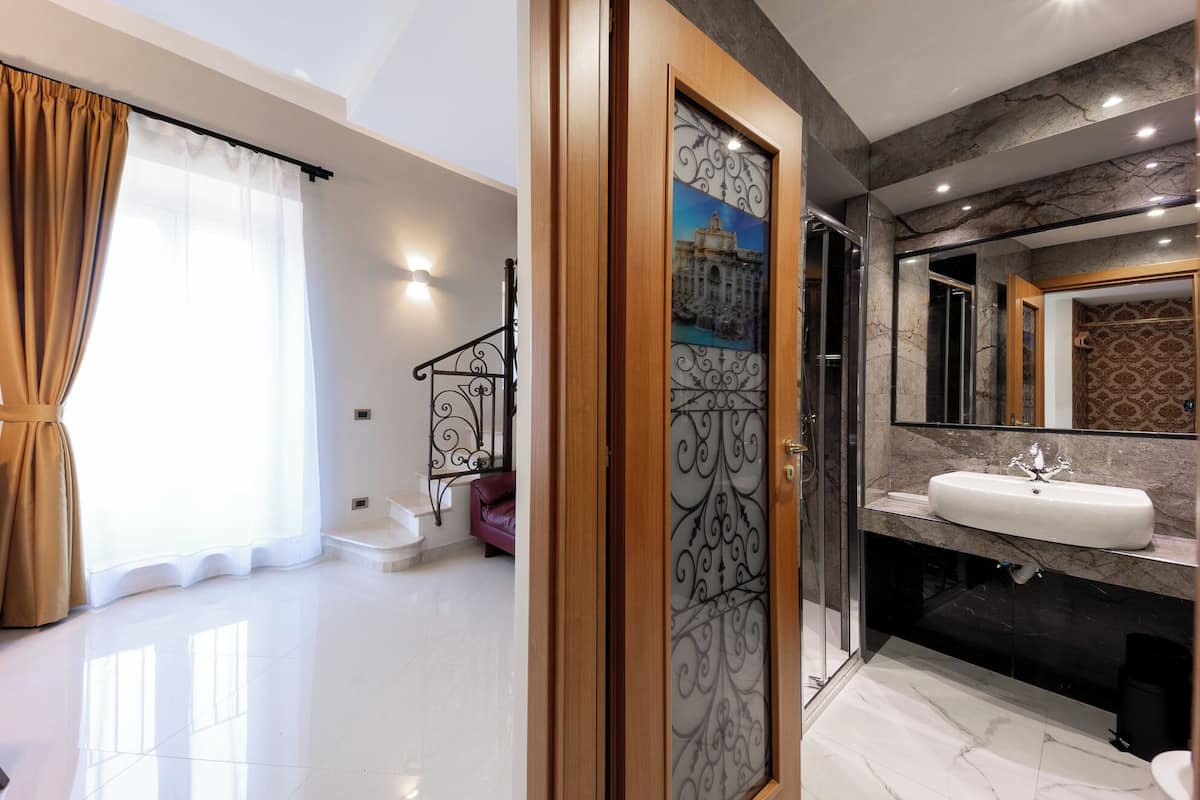 A modern bathroom with a large mirror, a white sink, and a shower area.