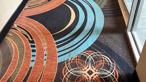 Un couloir d’hôtel avec des tapis à motifs et des lambris en bois.