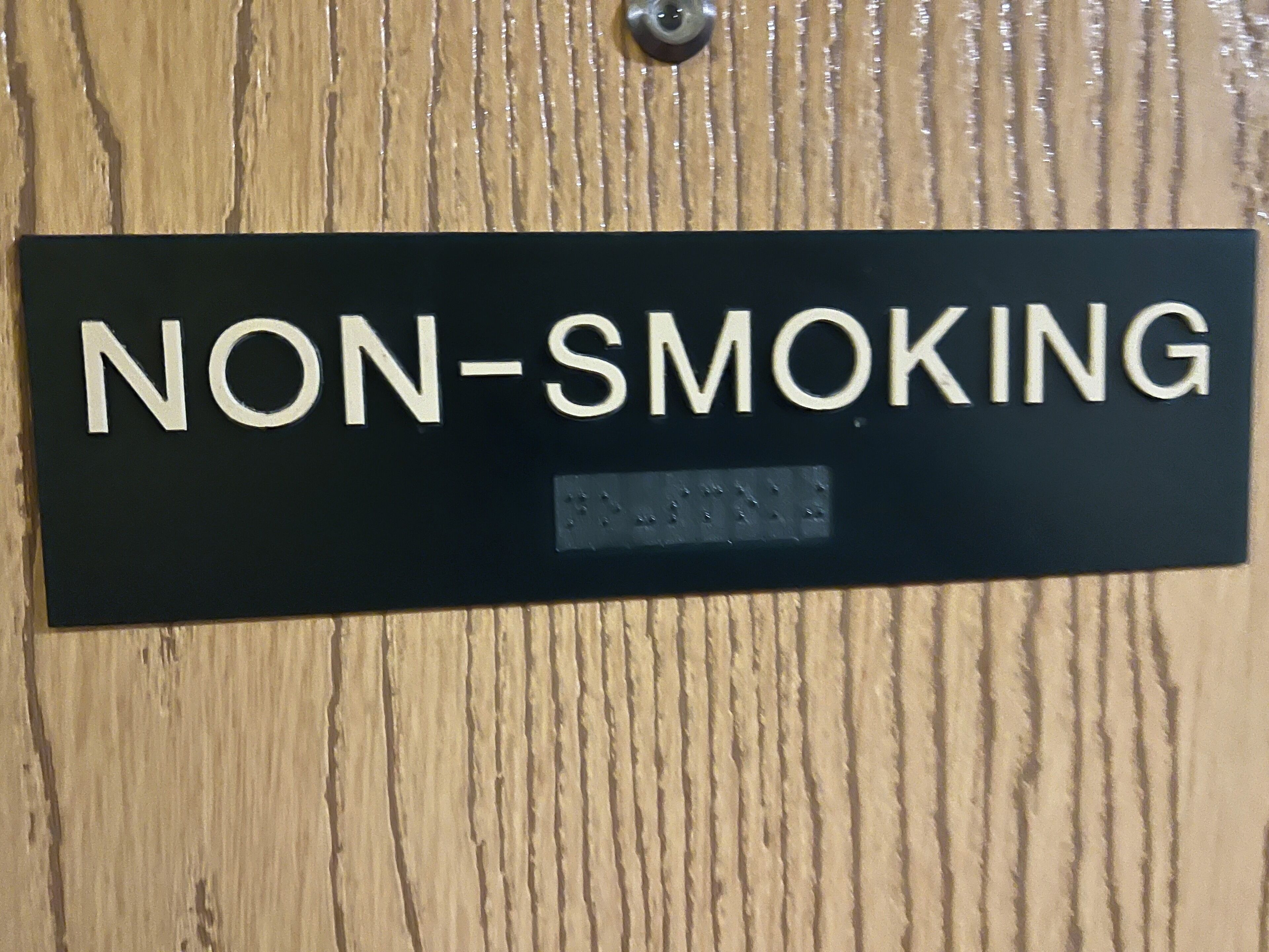 A black sign with white letters stating "NON-SMOKING" on a wooden surface.