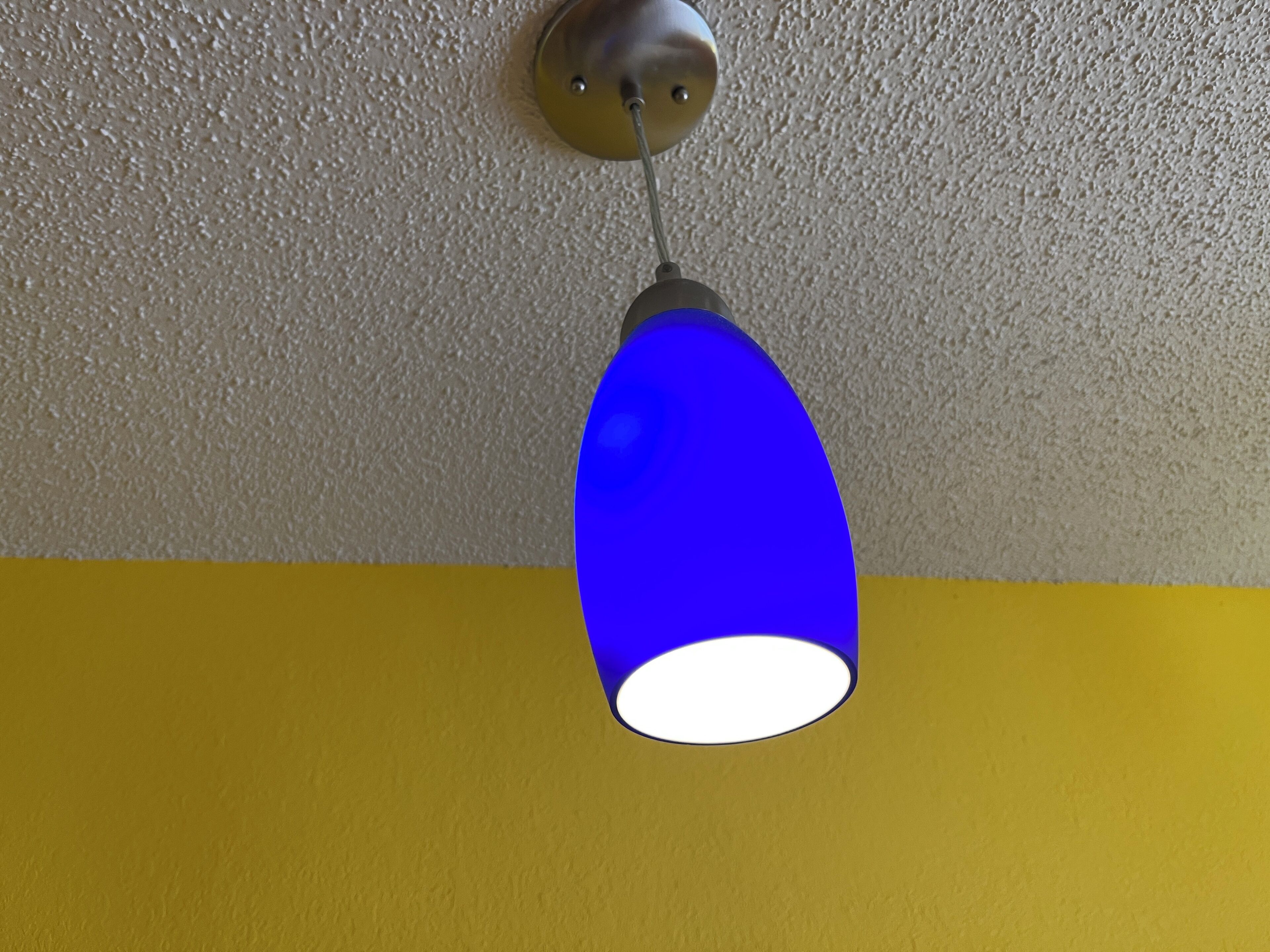 Una lámpara colgante con pantalla de vidrio azul.