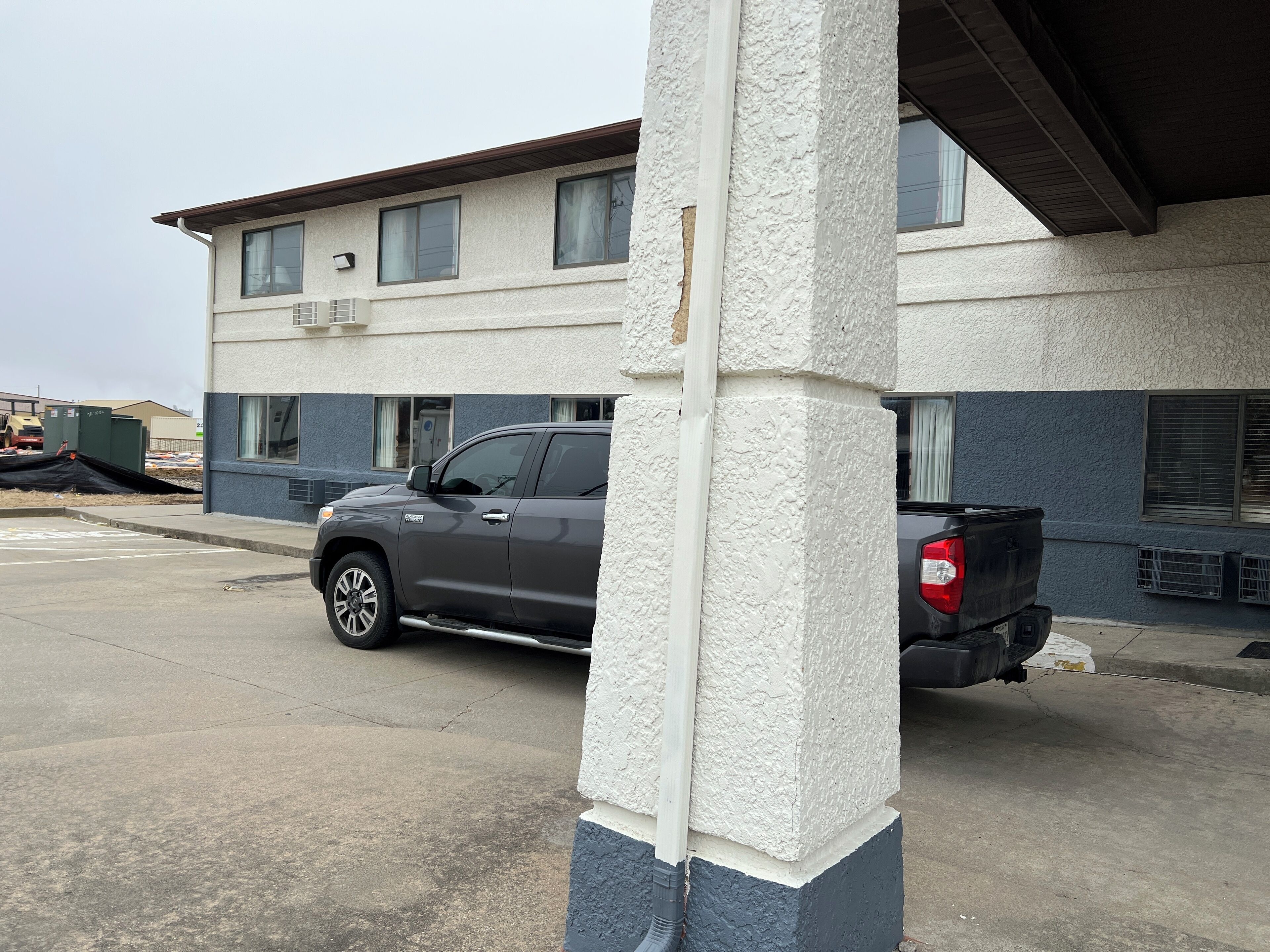 A building with a parking lot, a gray pickup truck, and a red truck in the background.