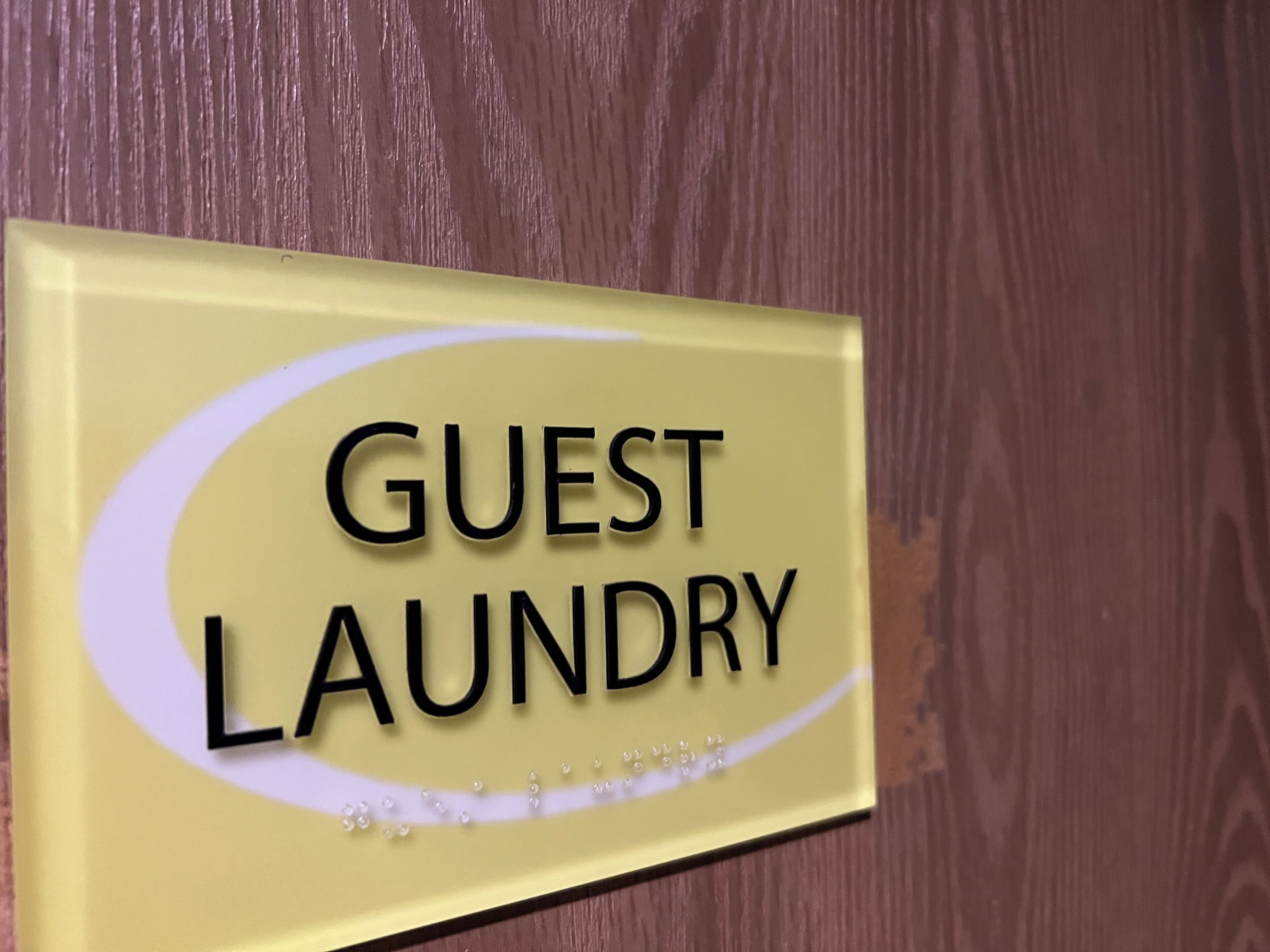 A sign with the text "GUEST LAUNDRY" on a yellow background with a white oval design.