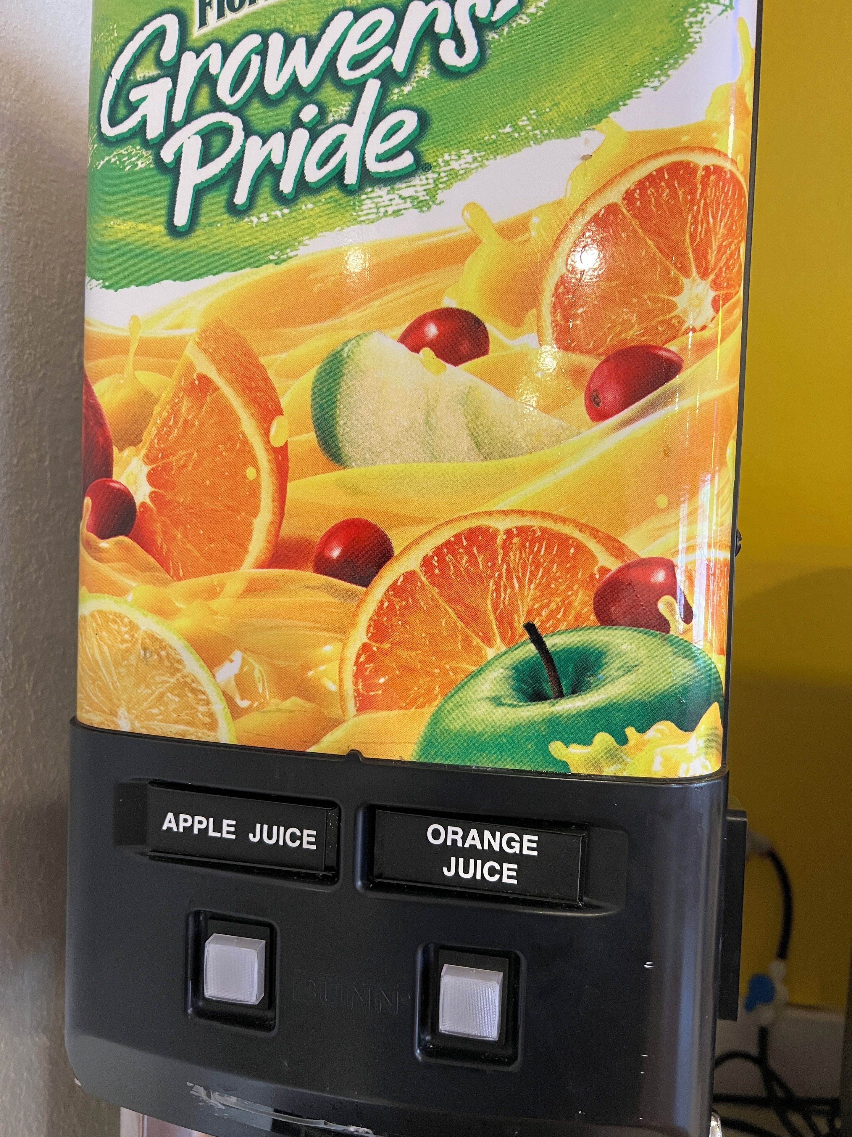 Un distributeur de jus avec une étiquette colorée représentant des fruits et le texte « Fierté des producteurs ».