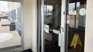 L’entrée d’un hôtel, avec une porte en verre, un panneau « Interdiction de fumer » et un panneau d’avertissement « Sol glissant ».