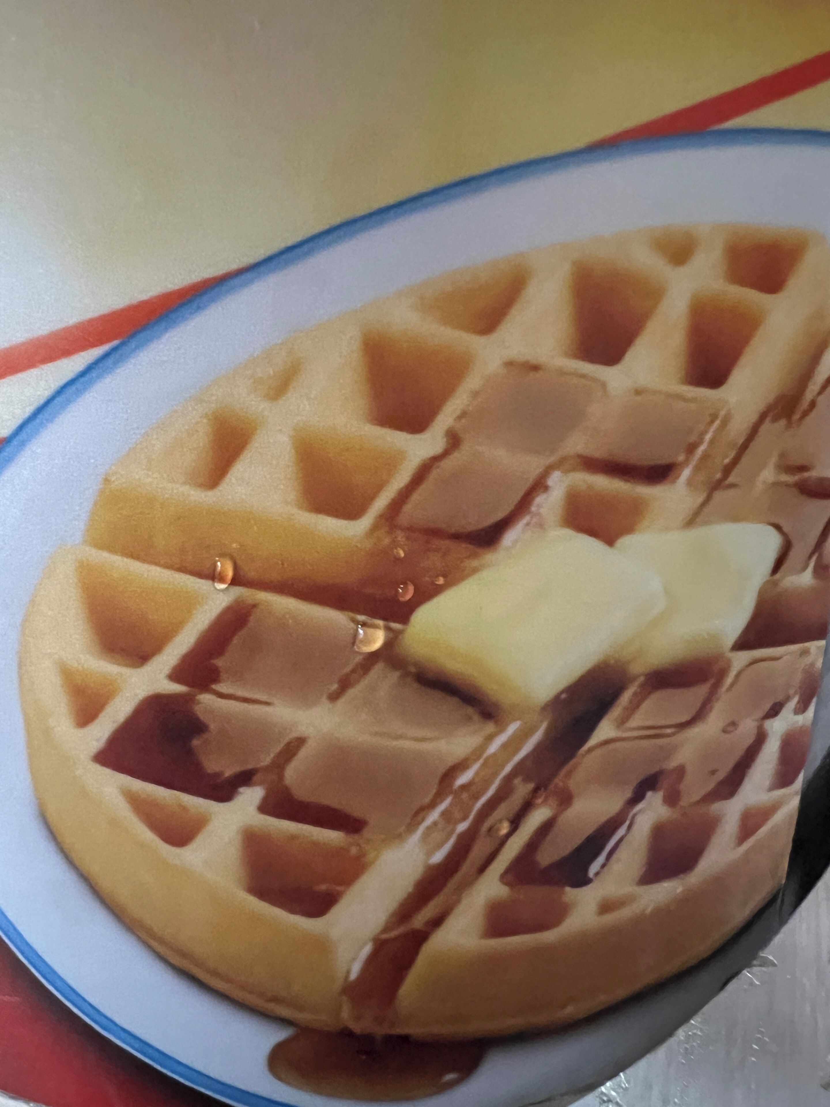 A waffle with syrup and butter on a plate.