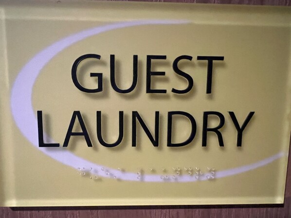 A sign with the words "GUEST LAUNDRY" on a beige background.