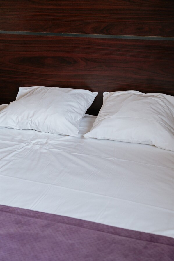 A bed with white bedding and a wooden headboard. - Hôtel - Restaurant La Caborne (Limonest)