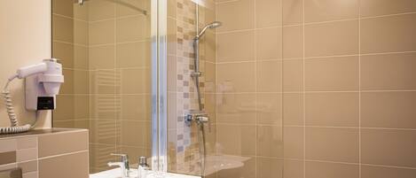 Une salle de bain moderne avec une douche à parois de verre, un lavabo et un sèche-cheveux posé sur le comptoir.