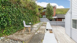 Un patio trasero con un porche, una terraza de madera y un sendero de piedra.