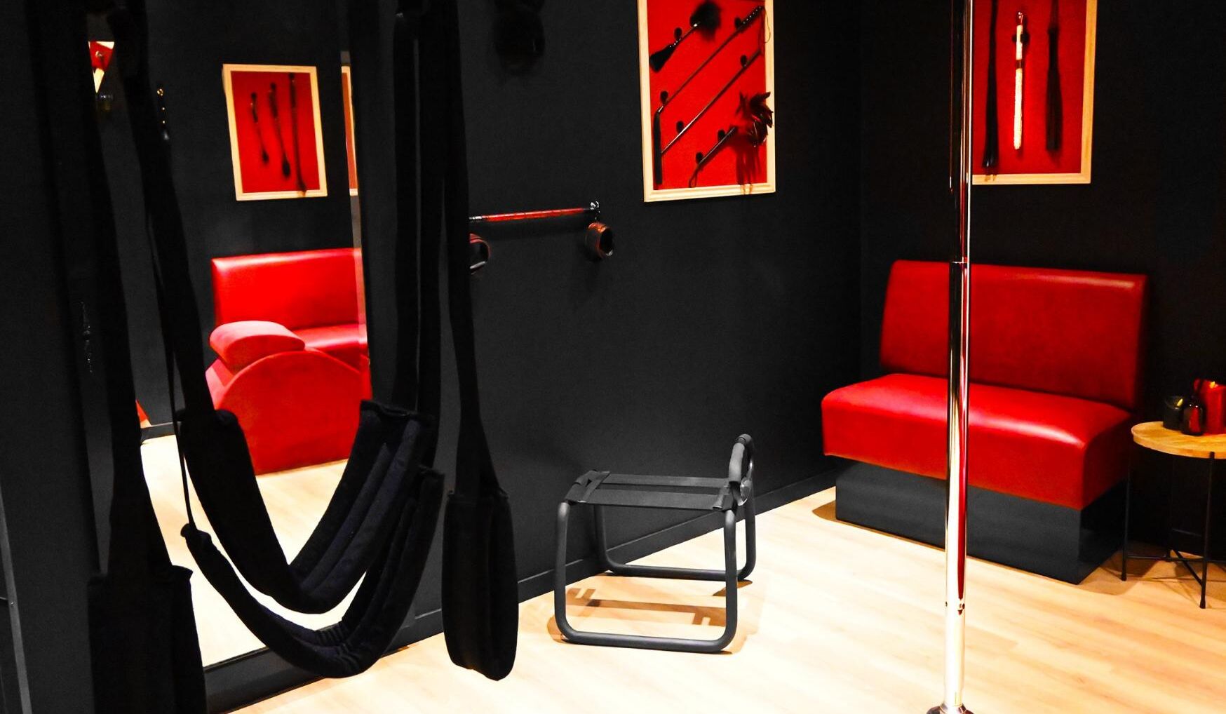 Ein Zimmer mit einem roten Sofa, einer Hängematte und einem kleinen Tisch mit einem Stuhl.