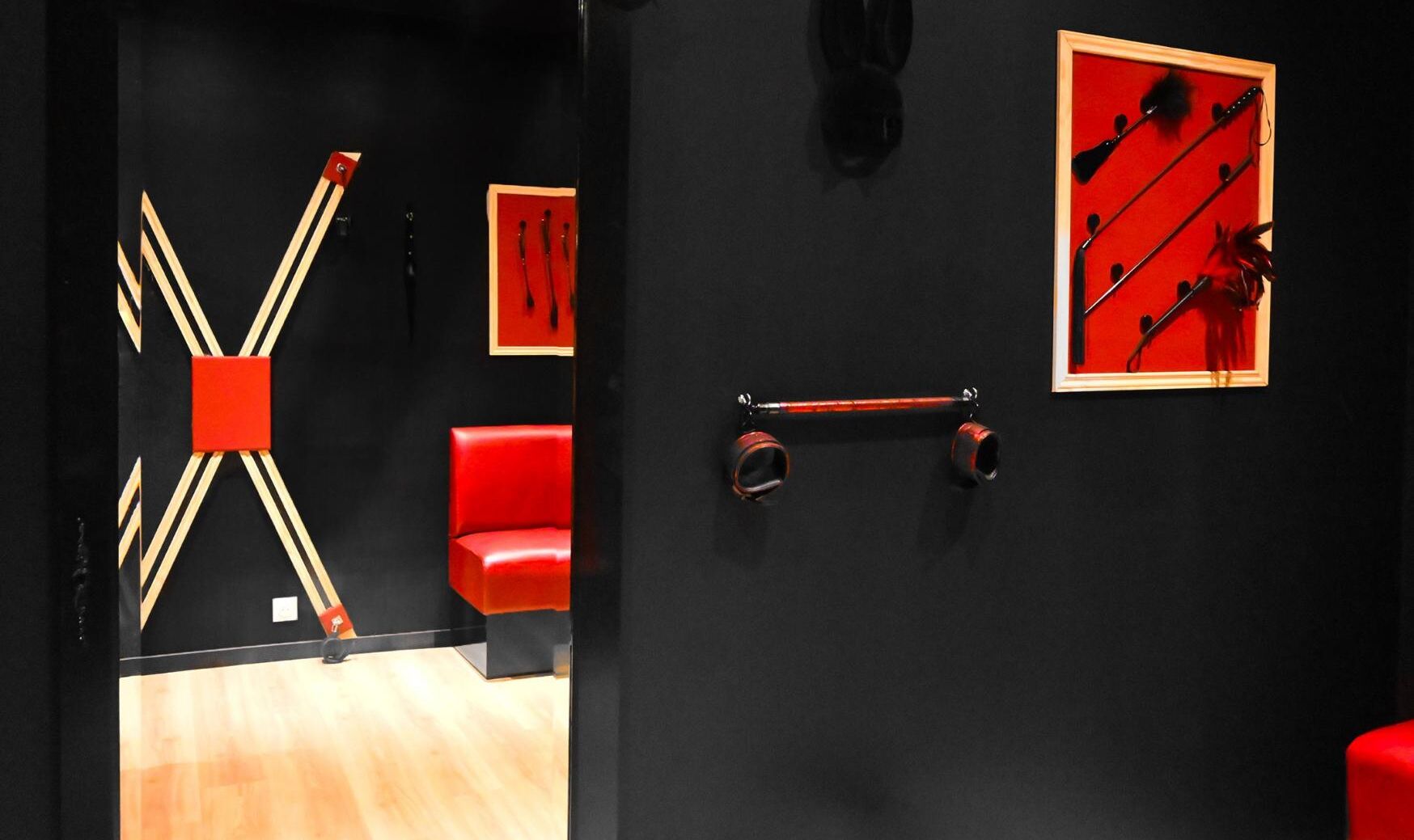 A room with a black wall, a red chair, and a wooden structure resembling a chair or table.