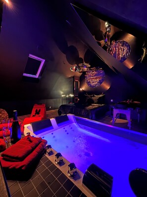 A modern spa area with a hot tub, seating, and ambient lighting. - La Sainteny Touch - Erotic Room (Terre-et-Marais)