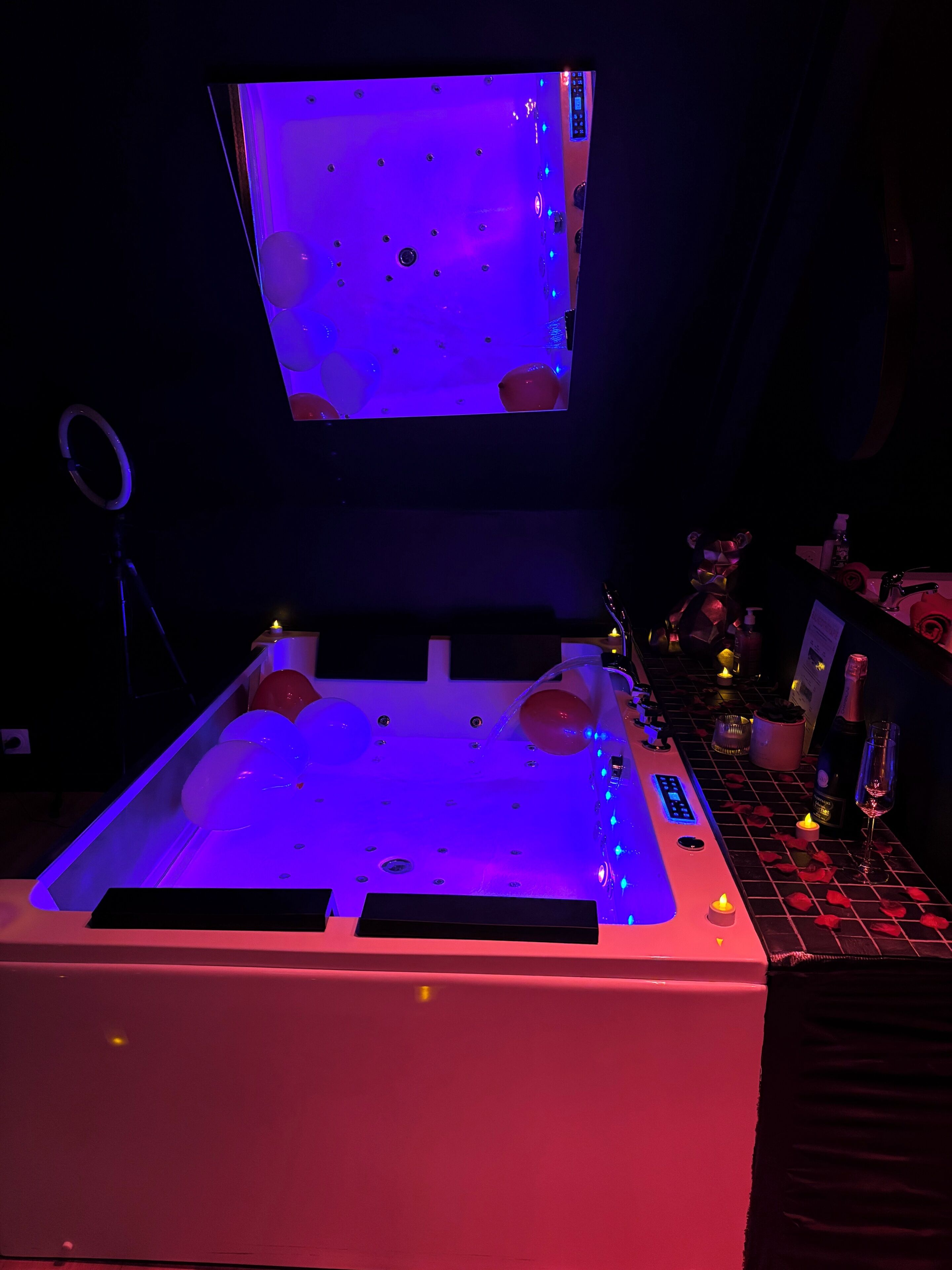 Une chambre dotée d’un grand lit, d’un téléviseur fixé au mur au-dessus du lit, et d’un coin bar agrémenté de bougies et de bouteilles.