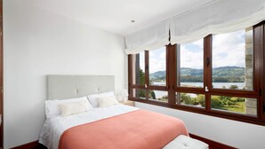 Una camera da letto con un letto grande, vista su un lago e pavimento in legno.