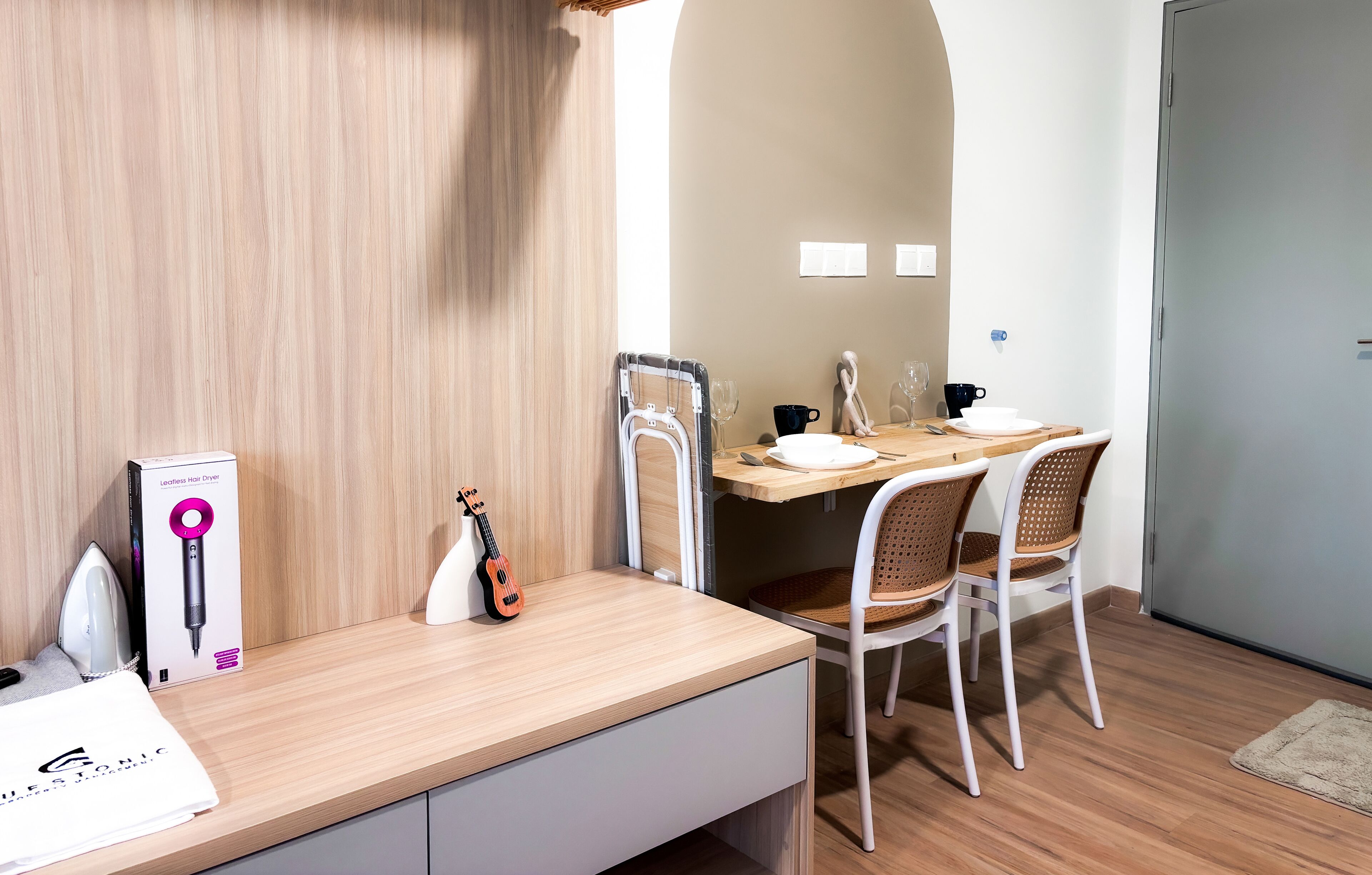 A modern dining area with a wooden table, white chairs, and a guitar. A hair dryer box is visible on the table.