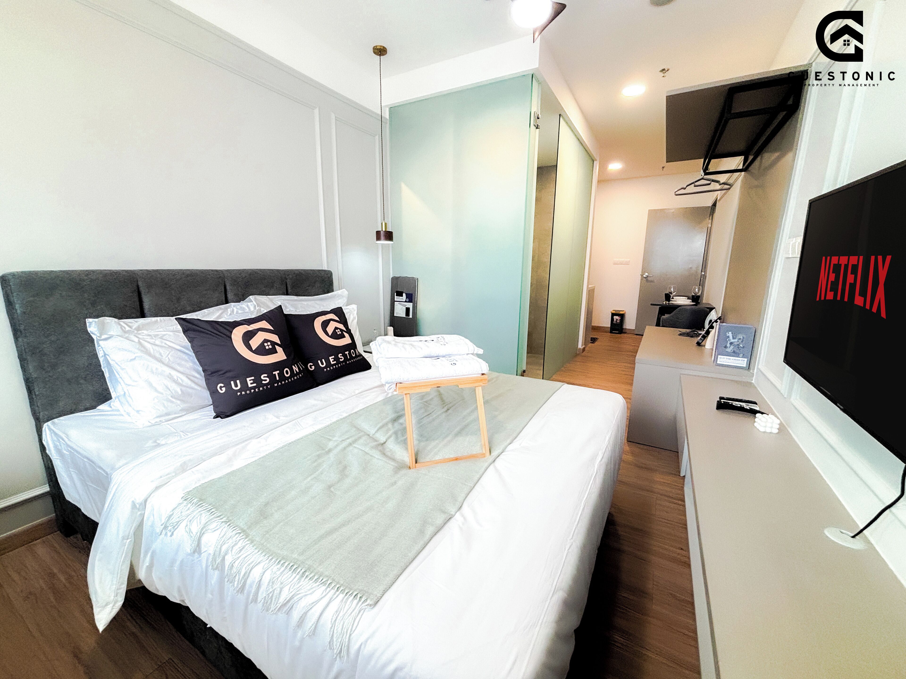 Een moderne hotelkamer met een bed, een bureau en een televisie waarop het Netflix-logo te zien is.