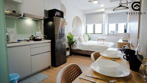 A modern kitchen with a refrigerator, microwave, and a dining area with a table set for two. - Riveria City KL Sentral by Guestonic (Kuala Lumpur)