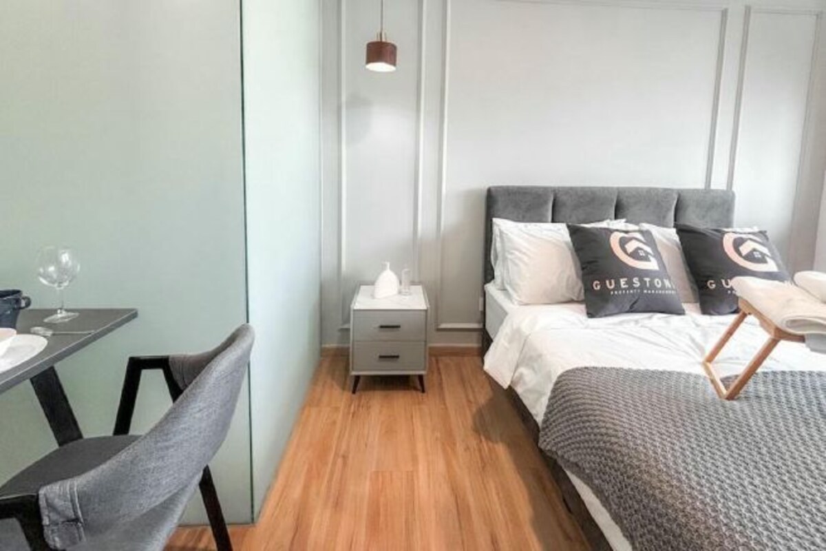 A modern bedroom with a bed, bedside table, and a small table with a chair.