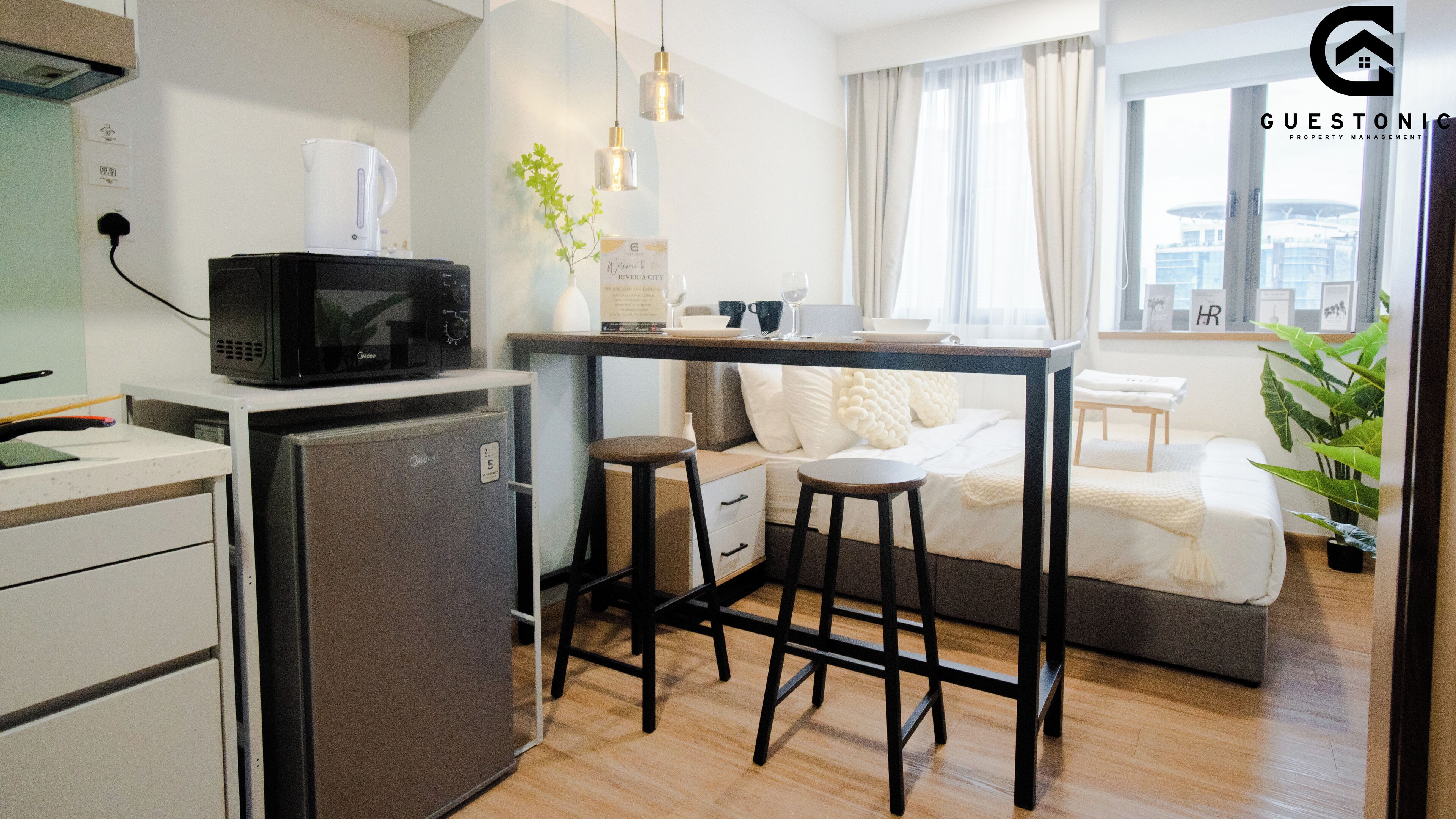 A compact kitchenette with a microwave, refrigerator, and a small bar area. There is a seating area with a sofa and a dining table.