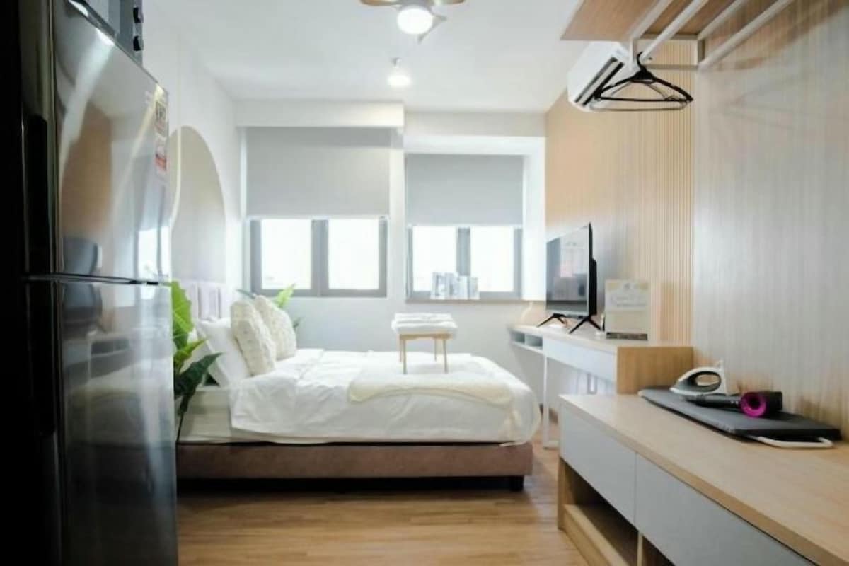 A modern bedroom with a bed, a television, and a small table.