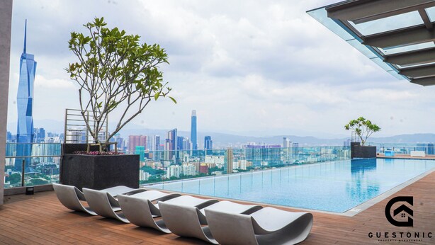 A rooftop pool with lounge chairs and a city view. - Riveria City KL Sentral by Guestonic (Kuala Lumpur)