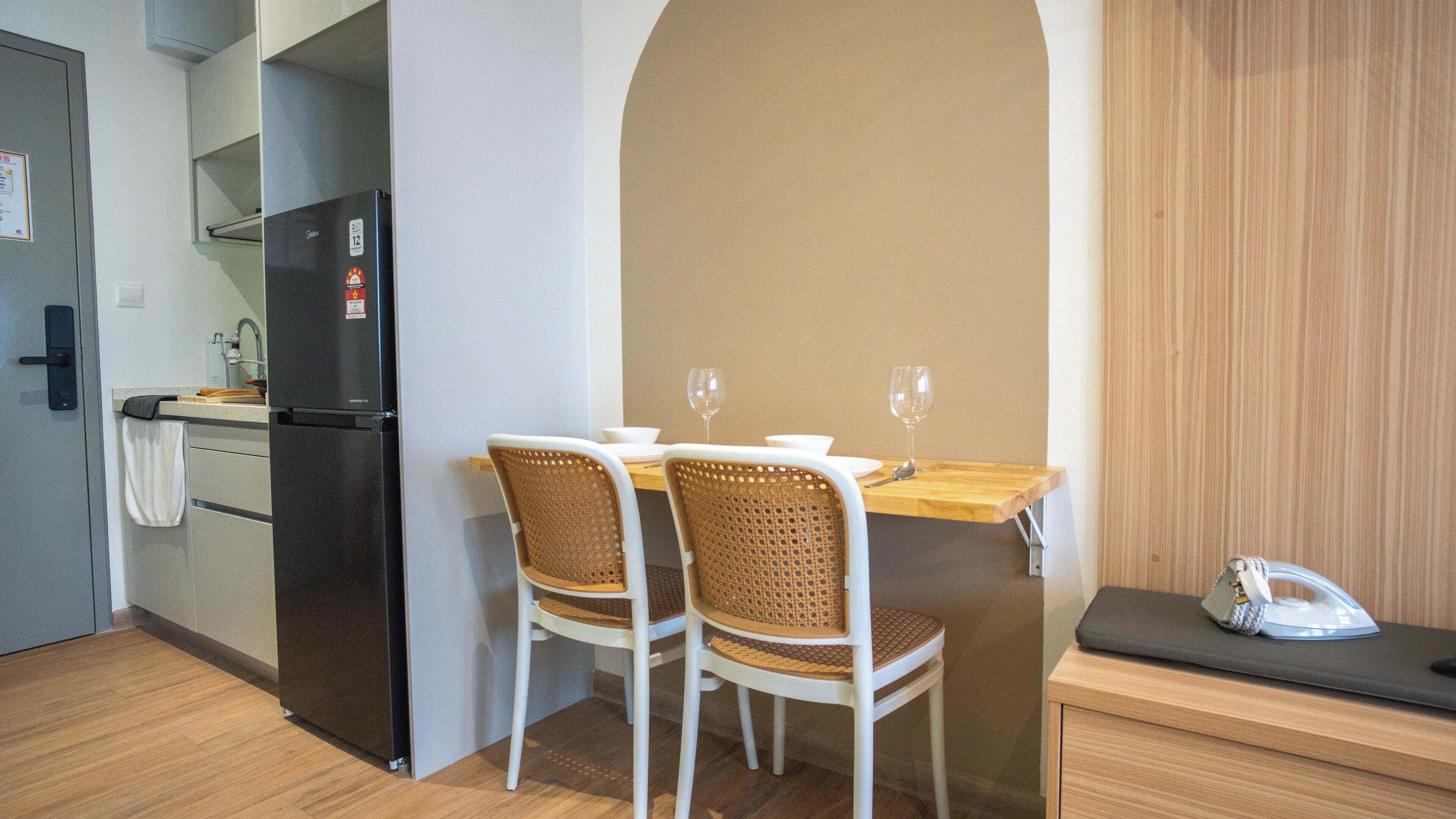 Una cocina compacta con refrigerador, una mesa de comedor con dos sillas y una pequeña encimera.