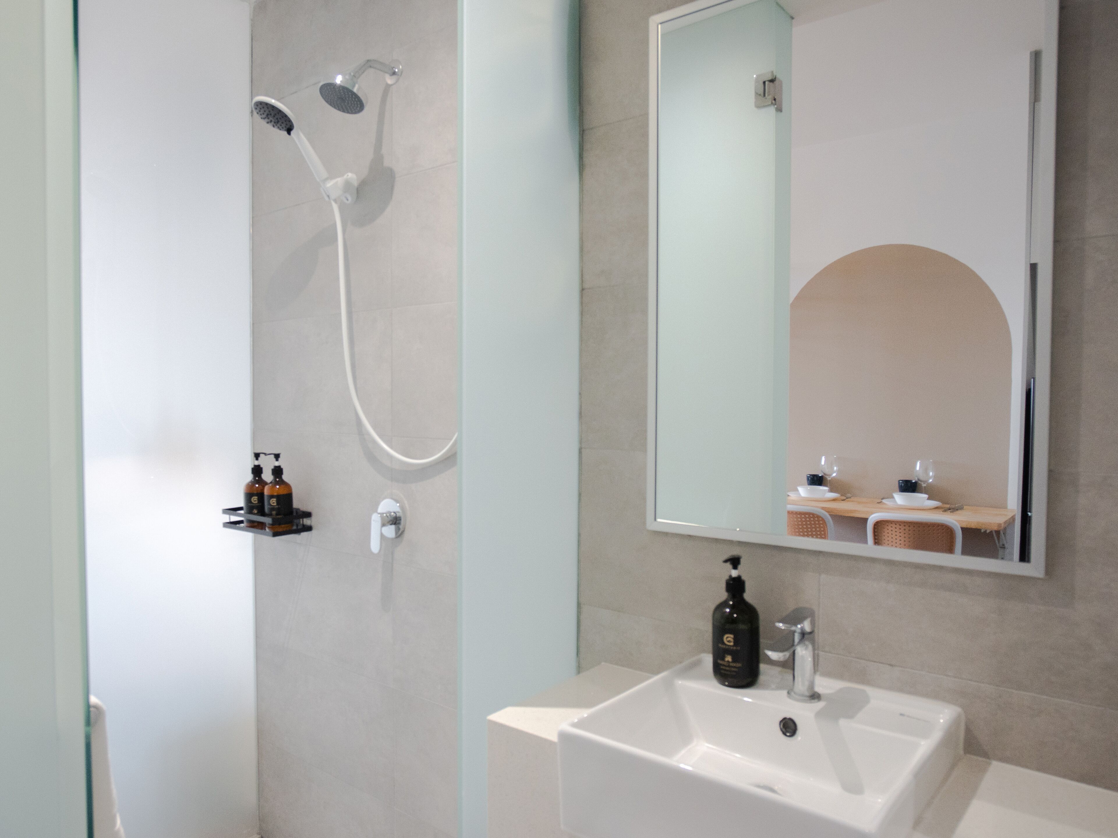 Un baño moderno con ducha, lavamanos y espejo.