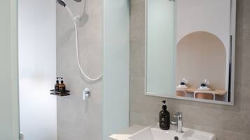 Un baño moderno con ducha, lavamanos y espejo.