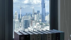 A view of a cityscape through a window, featuring a tall skyscraper and a tower. - Riveria City KL Sentral by Guestonic (Kuala Lumpur)