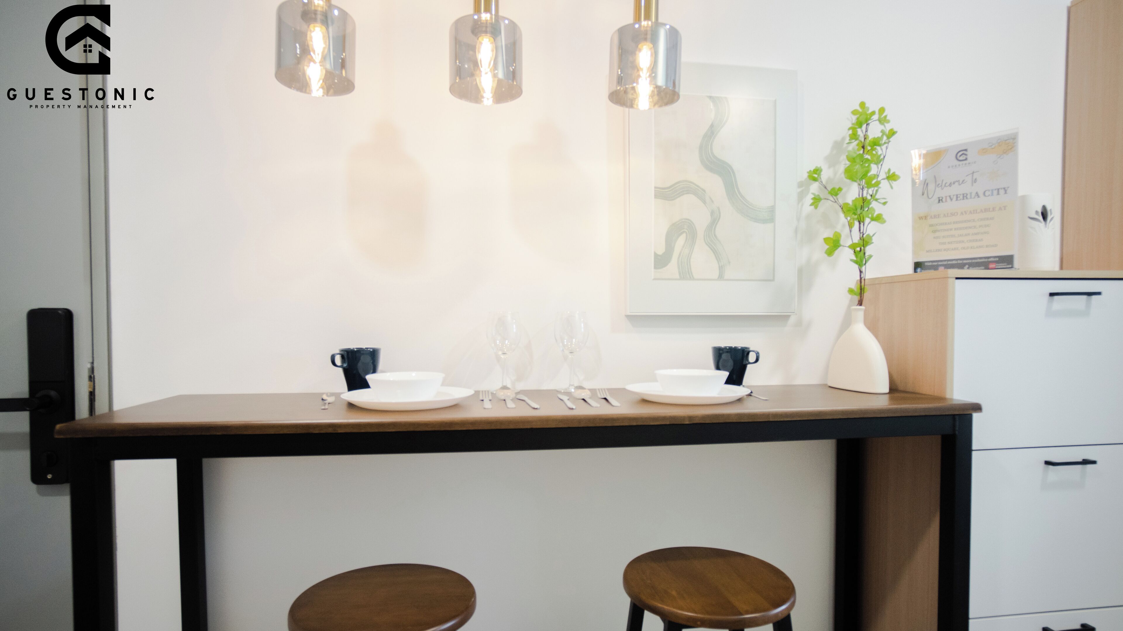 Una cocina moderna con encimera de madera, lámparas colgantes y un florero con hojas verdes.