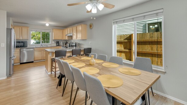 A modern kitchen with wooden cabinets, a built-in oven, and a dining area with a large table and chairs. - 3-bedroom house, good for families (Vancouver)
