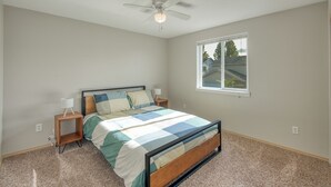 A bedroom with a bed, a ceiling fan, a window, and a view of a house outside. - 3-bedroom house, good for families (Vancouver)