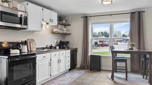 A modern kitchen with white cabinets, a black oven, and a dining area with a table and chairs.