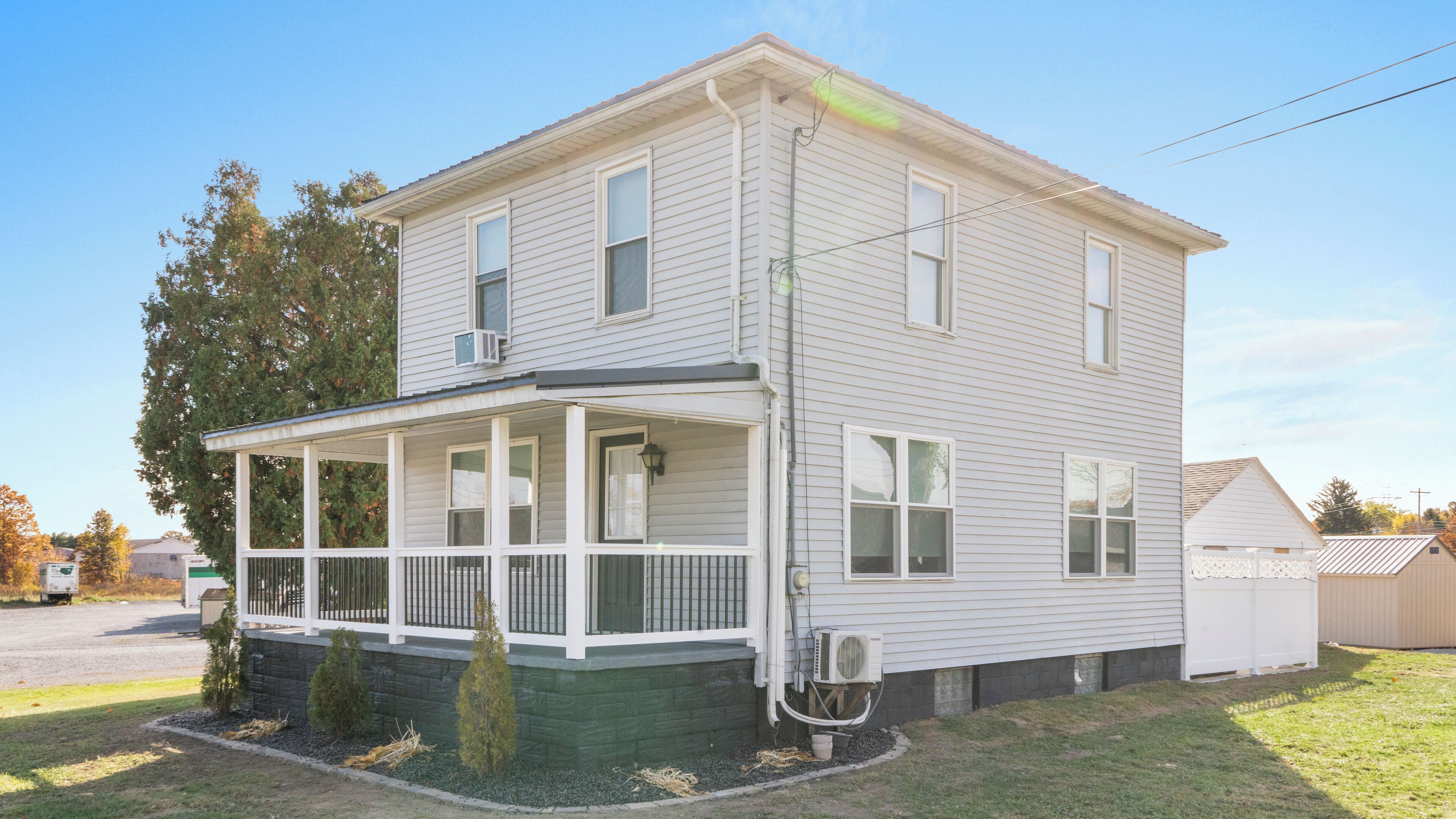 A two-story house with a covered porch and a small front yard.